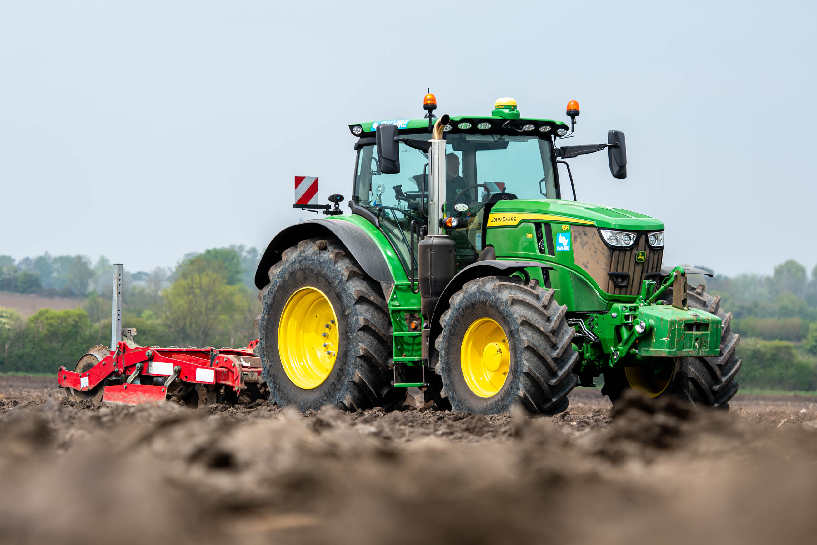 John Deere 6R 215 with Sub-Soiler implement in a field